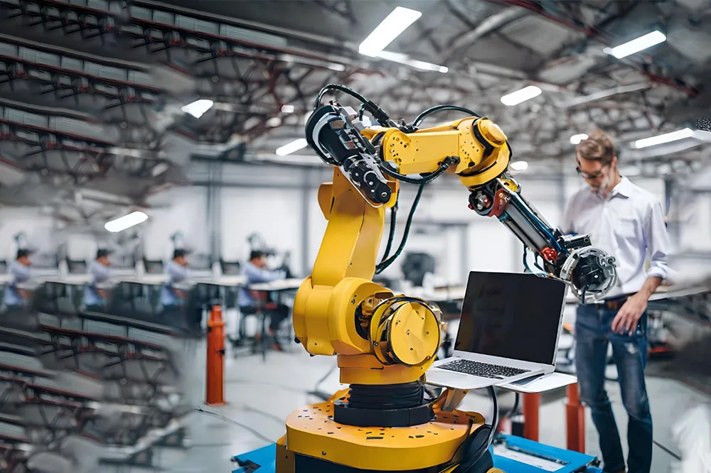 Engineer programming an industrial robot arm from a laptop