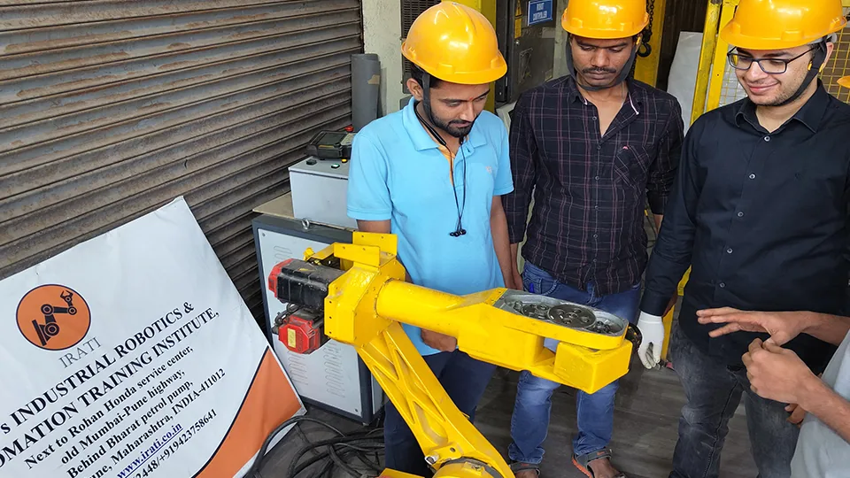 WO's IRATI trainees examining an industrial robot arm during a hands-on session
